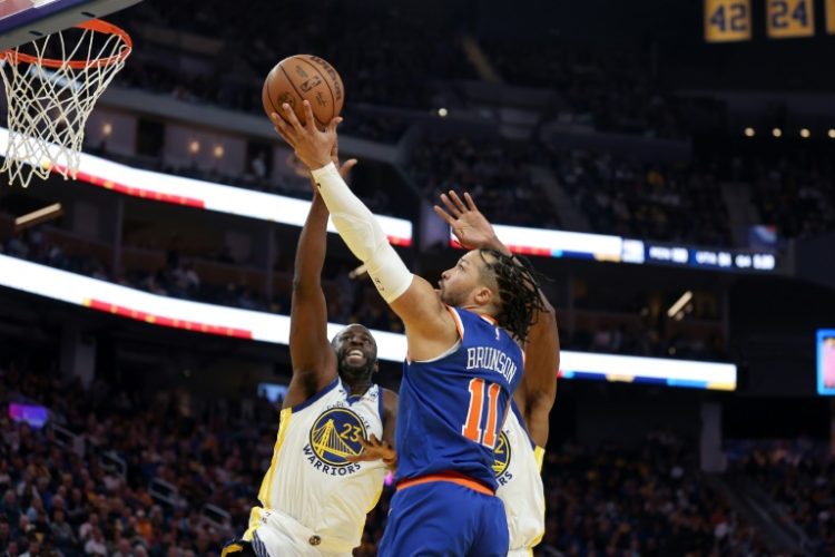 New York Knicks talisman Jalen Brunson soars over Golden State's Draymond Green on his way to a 34-point performance. ©AFP
