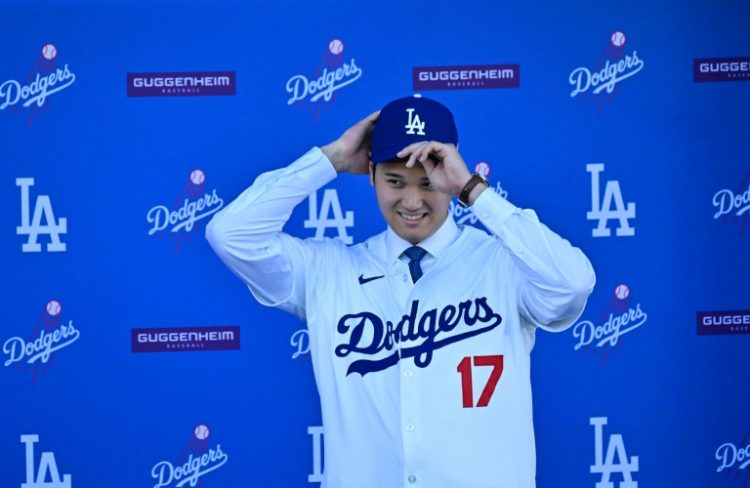 Japanese superstar Shohei Ohtani dons the cap and jersey of his new Major League Baseball club, the Los Angeles Dodgers. ©AFP