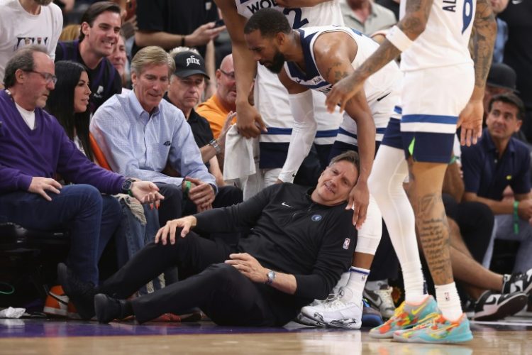 Minnesota Timberwolves head coach Chris Finch grabs his leg in pain after a sideline collision with Minnesota's Mike Conley in an NBA playoff game against the Phoenix Suns. ©AFP