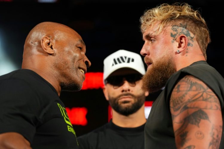 Mike Tyson, left, and Jake Paul, right, stare at each other while promoter Nakisa Bidarian, center, looks on ahead of their heavyweight boxing showdown, which has been rescheduled for November 15. ©AFP
