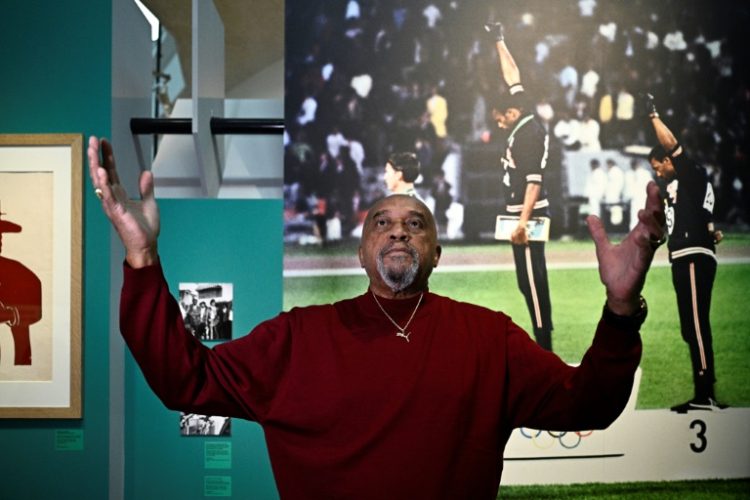 Tommie Smith poses in front of  the emblematic photograph of the 1968 Mexico City Olympics . ©AFP