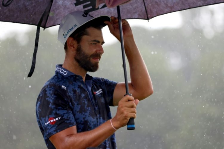 South African Erik van Rooyen stands under an umbrella during a Wednesday practice at the PGA Tour Wyndham Championship, where organizers have postponed the opening round to Friday due to a tropical storm. ©AFP