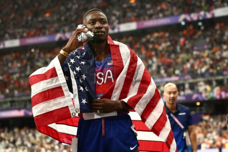 American Grant Holloway holds his shoe while celebrating. ©AFP