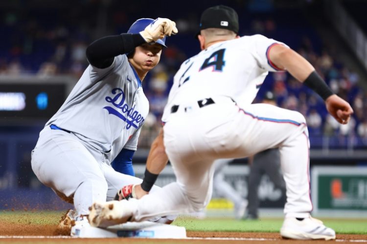 Dodgers star Shohei Ohtani beats the tag by Miami Marlins third baseman Connor Norby to post his 50th stolen base of the MLB season. ©AFP