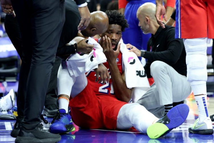 Philadelphia 76ers star Joel Embiid is attended by medical staff after taking a blow to the face in an NBA loss to the Indiana Pacers. ©AFP